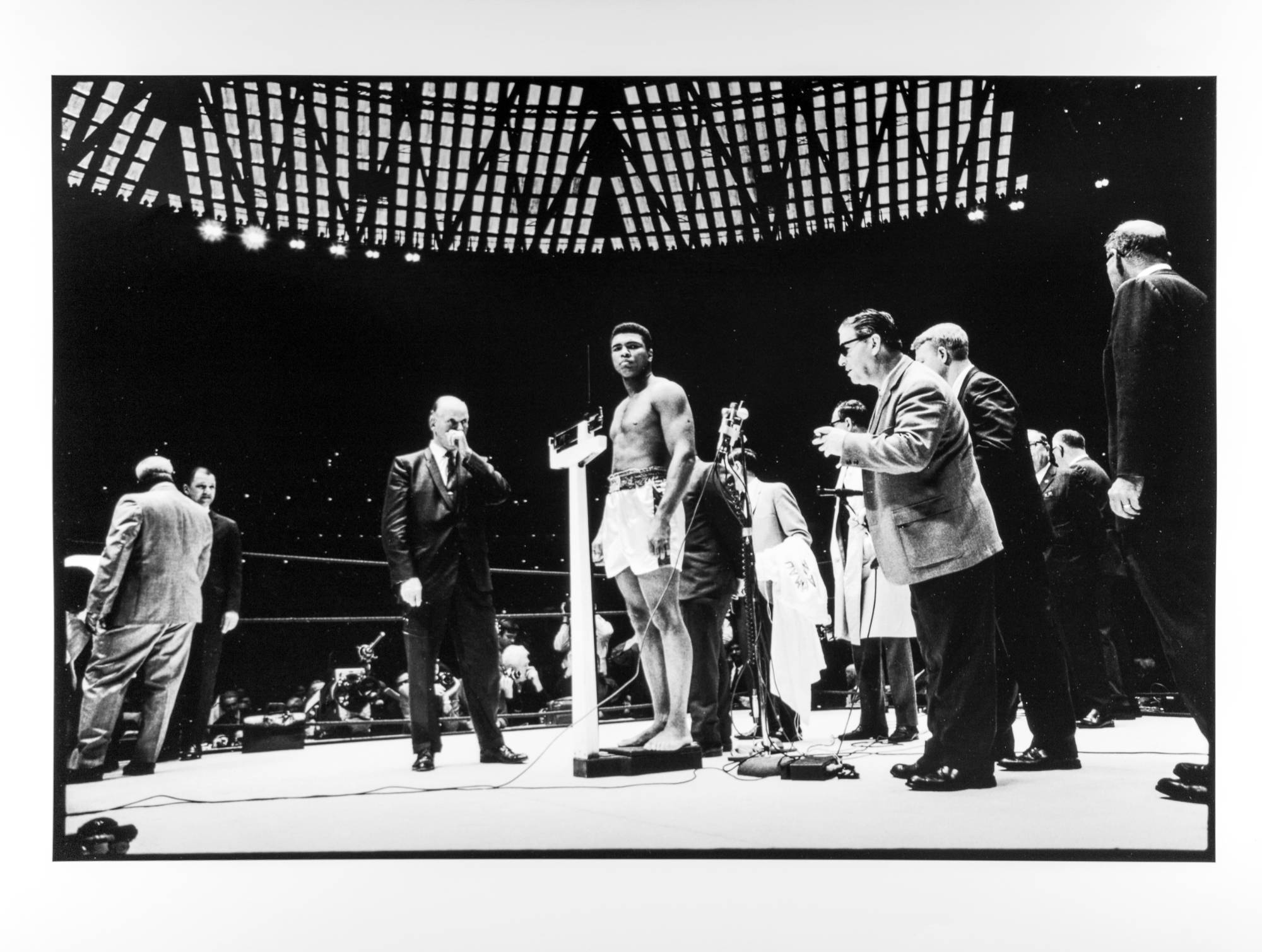 Boxer Mohammed Ali weighing-in for a fight in the middle of a boxing ring